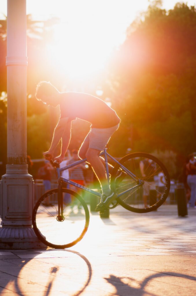 Rider et pignon fixe en l’air à contre-jour dans une lumière chaude.
