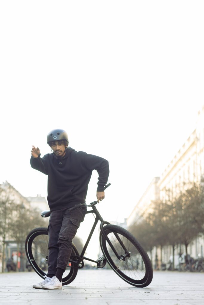 Rider faisant un pas à côté d’un vélo noir incliné après un trick.