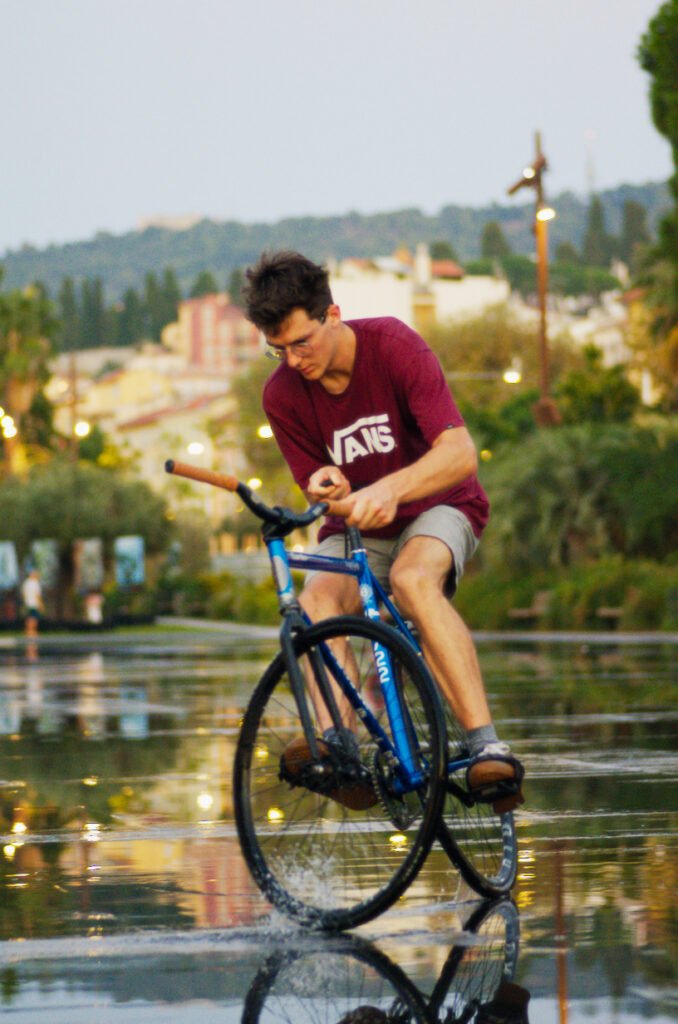 Rider penché dans un virage sur un vélo bleu au bord de l’eau.