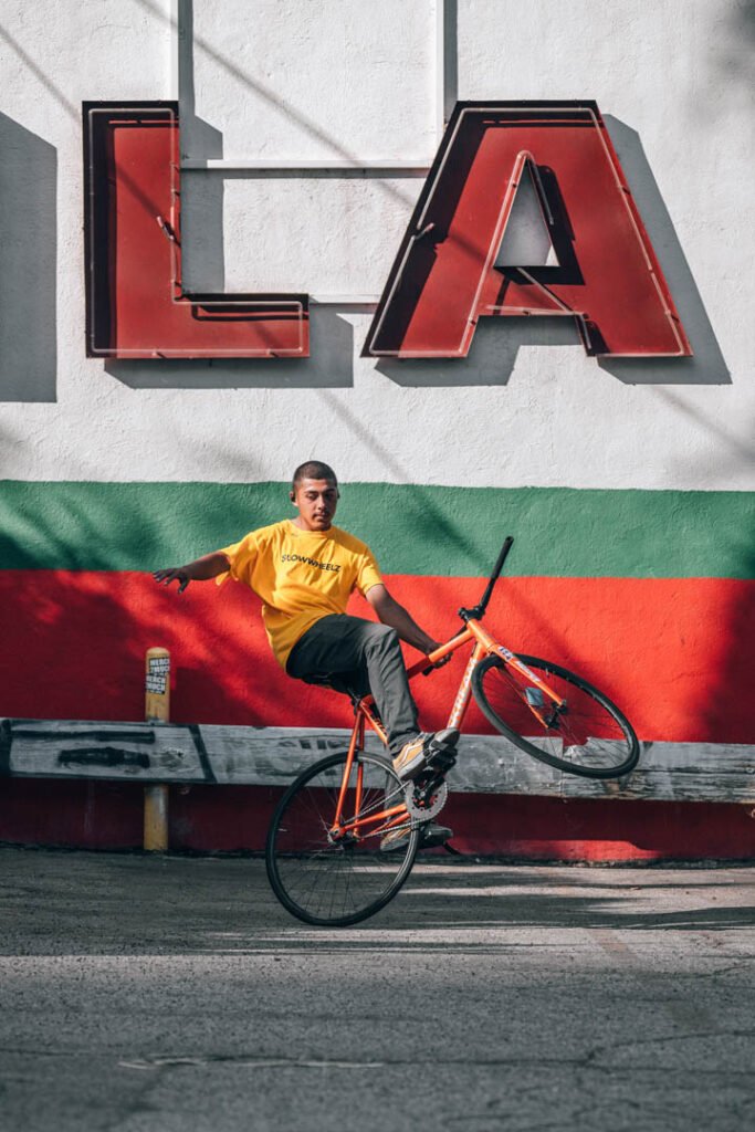 Rider en T-shirt jaune levant la roue avant devant un mur peint.