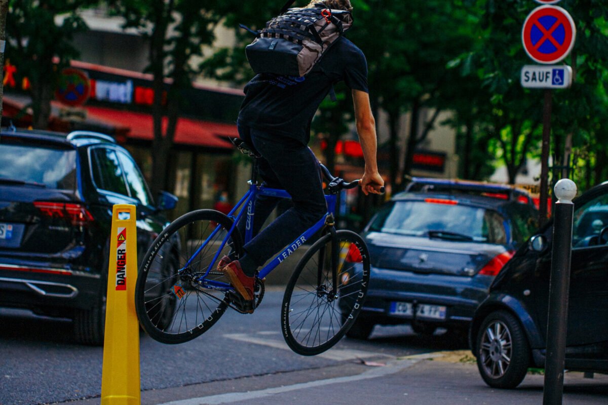 Rider décollant les deux roues d’un vélo bleu dans une rue.