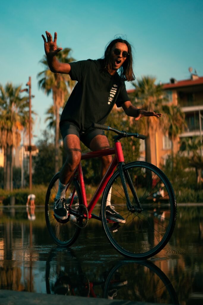 Rider levant une main en faisant tourner un vélo rouge dans l’eau.