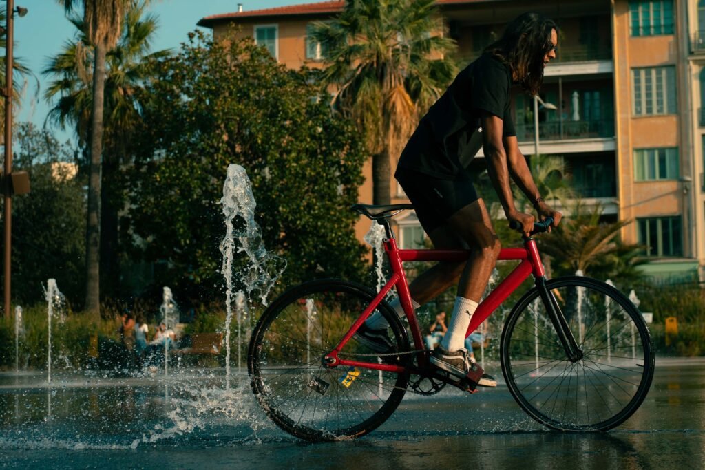 Rider traversant le miroir d’eau sur un pignon fixe rouge au coucher du soleil.