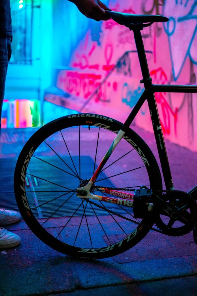 Partie arrière d’un pignon fixe devant un mur éclairé en rose et bleu.