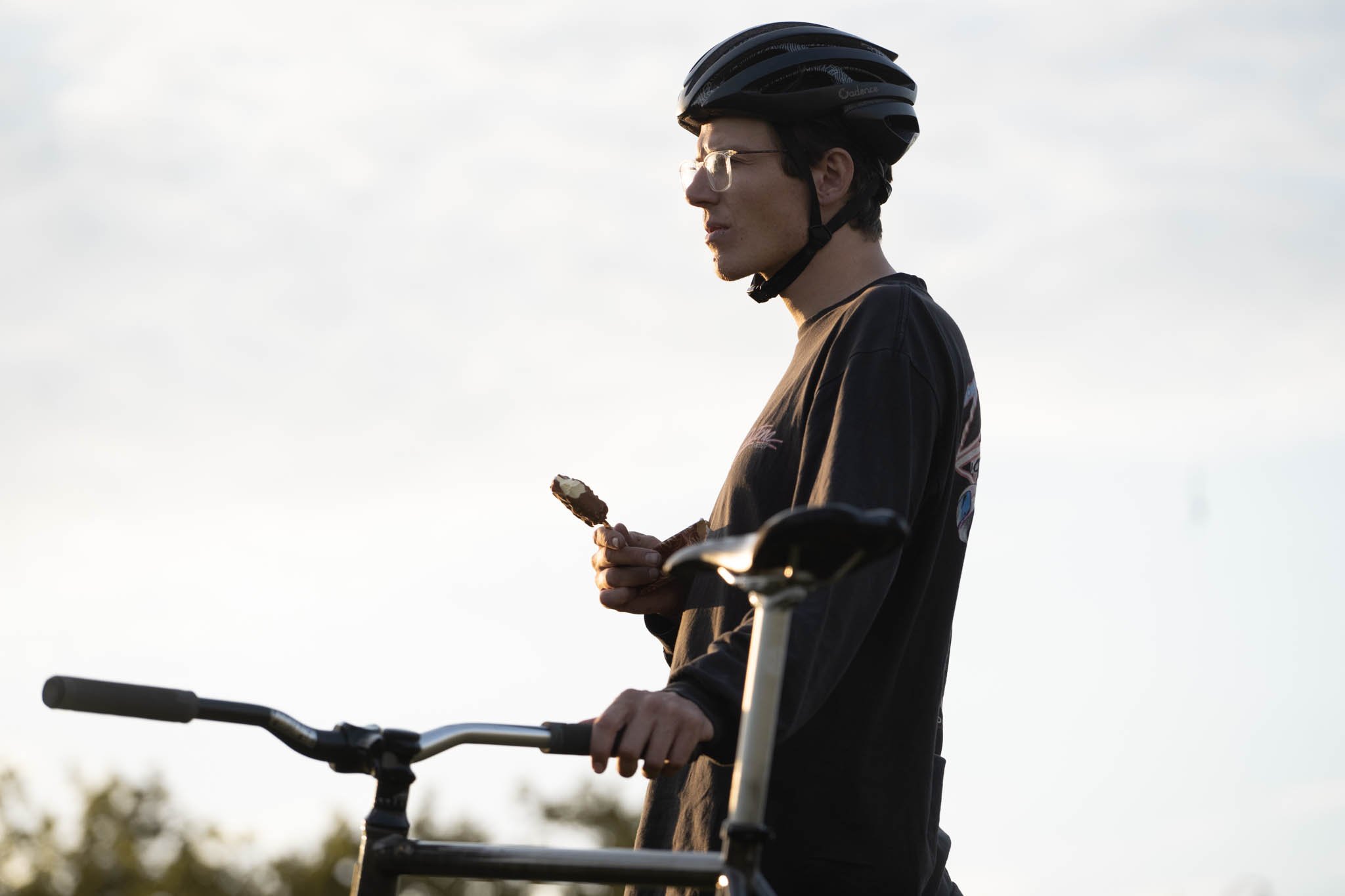 Jackson à côté de son vélo, casque sur la tête et téléphone à la main.