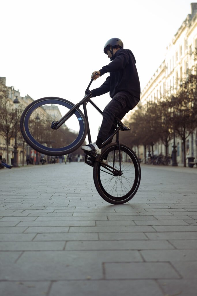 Rider casqué en équilibre haut sur la roue arrière sur une place.
