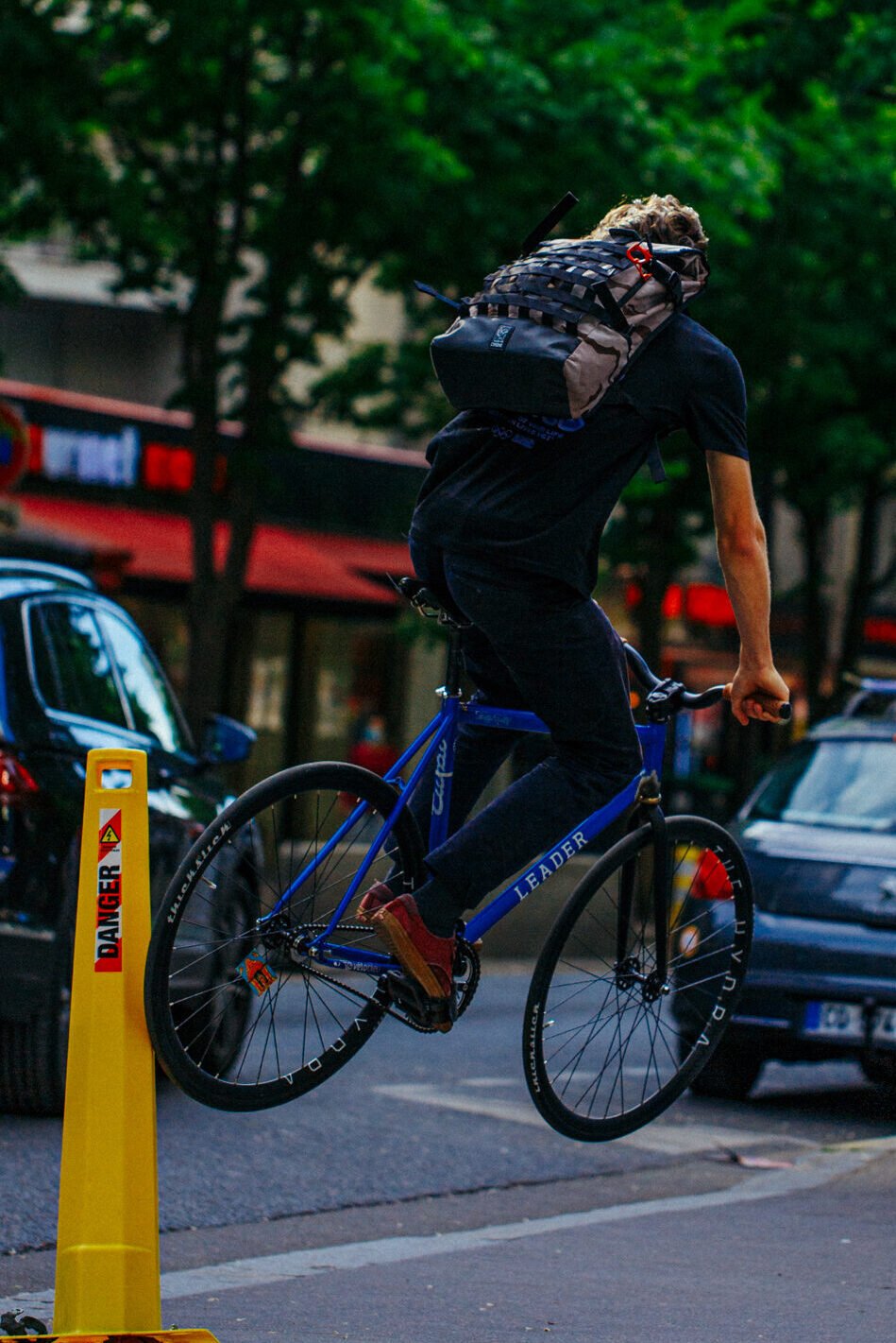 Rider et vélo bleu en l’air à côté de voitures garées.