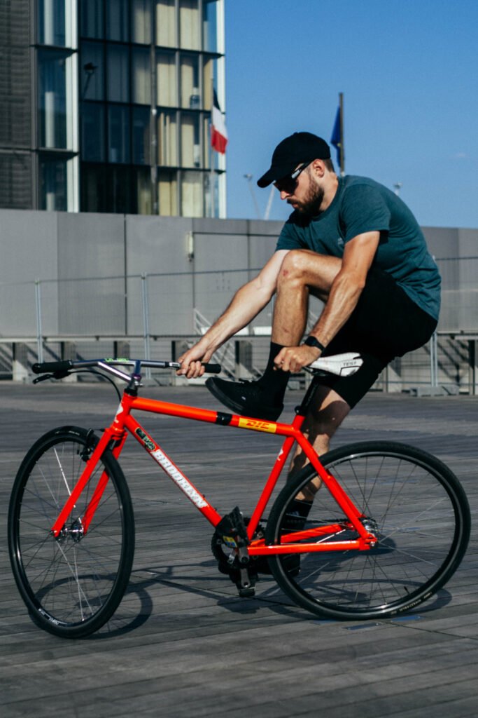 Rider tenant la selle et le cintre d’un pignon fixe rouge.