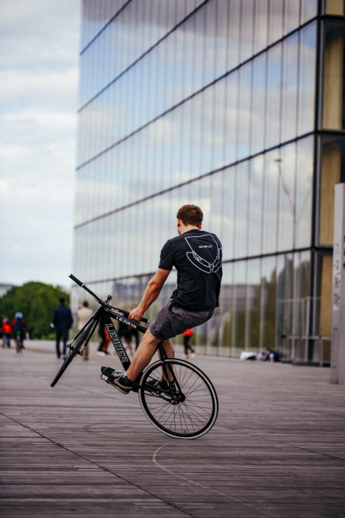 Rider levant la roue avant devant un bâtiment vitré.