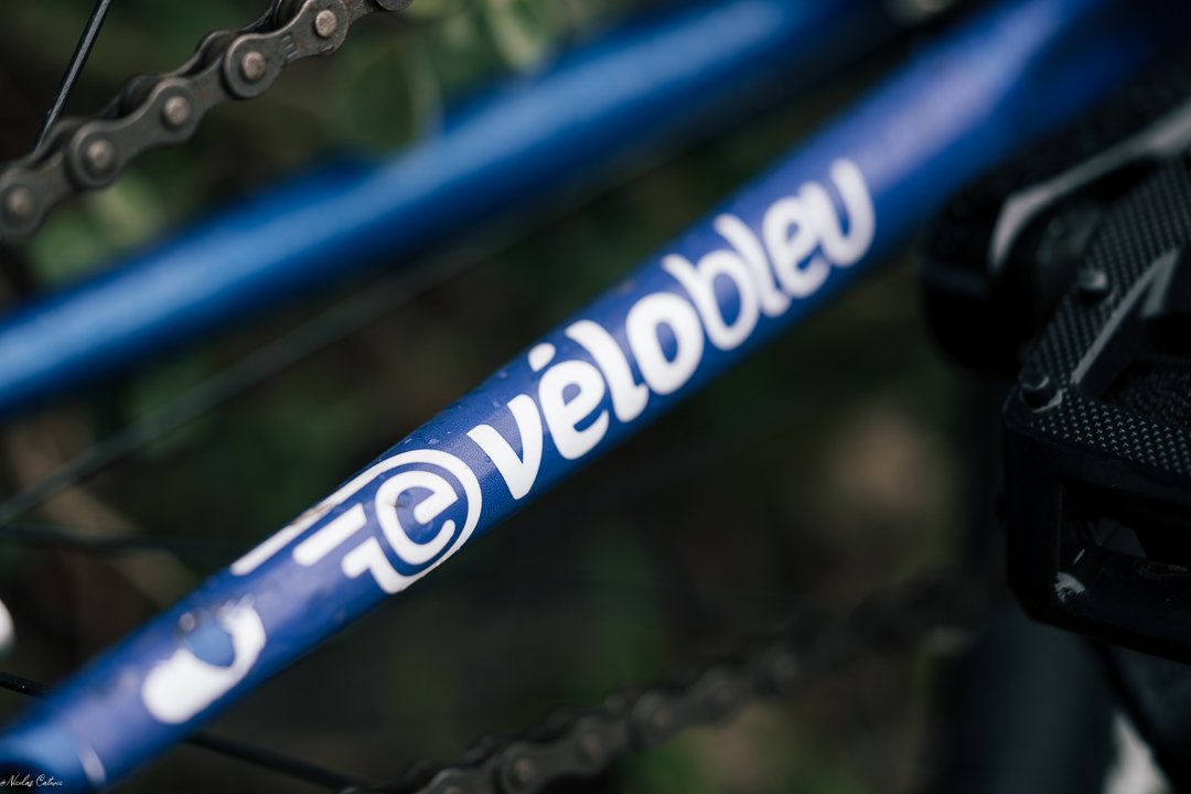 Tube de cadre bleu portant un autocollant VéloBleu blanc.