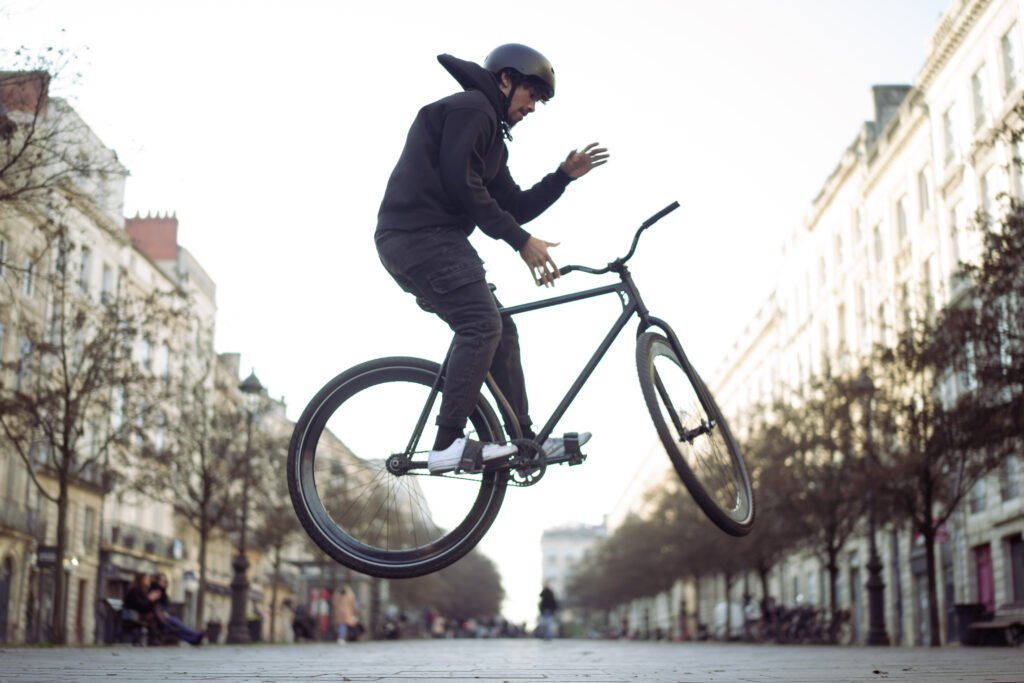 Rider et pignon fixe noir en l’air au-dessus des pavés.