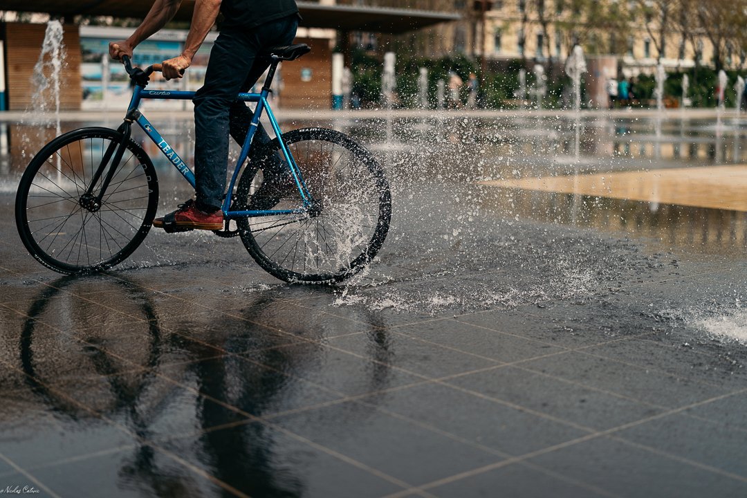 Rider faisant un skid sur un fixie bleu, sur un sol mouillé.