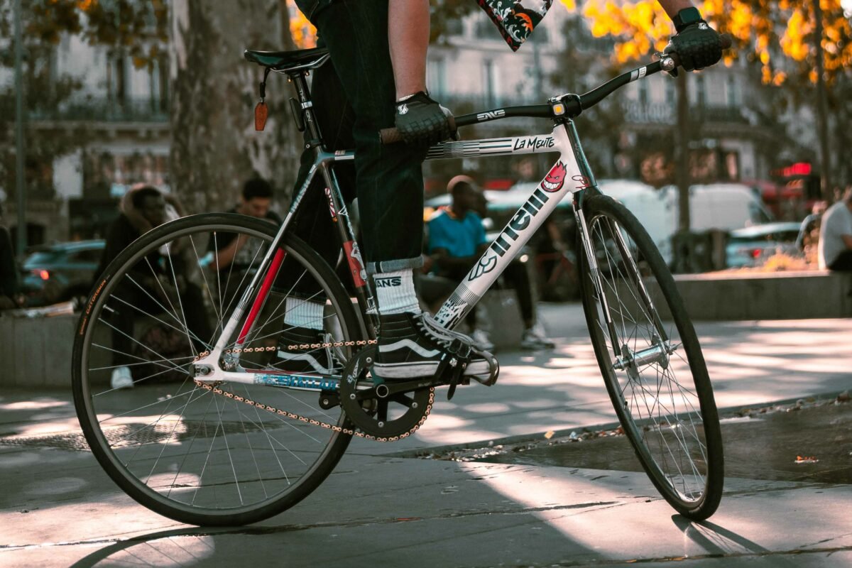 Fixie posé près d’une petite table dans une rue ensoleillée.