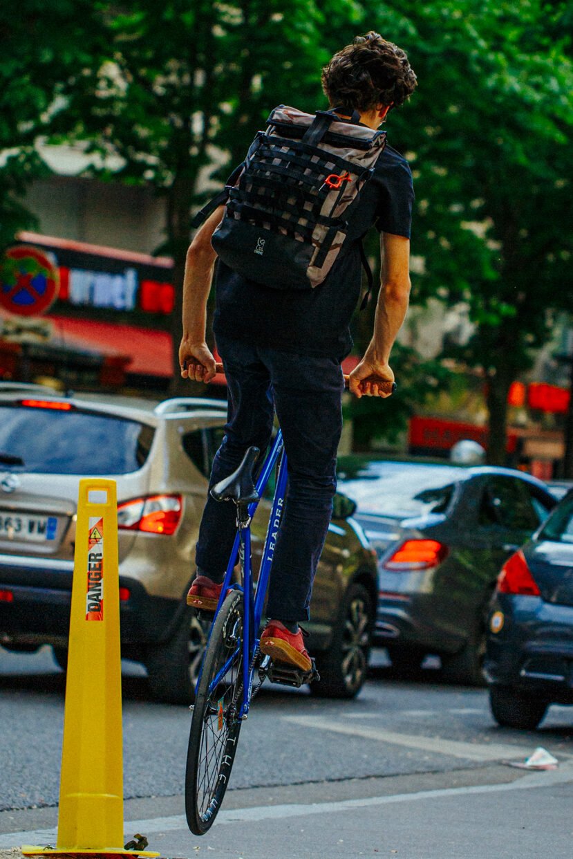 Rider levant la roue avant d’un vélo bleu près d’un potelet jaune.