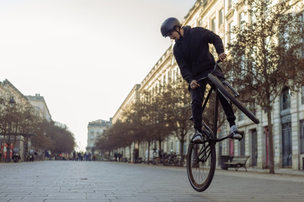 Rider casqué penché vers le cintre, roue avant levée.