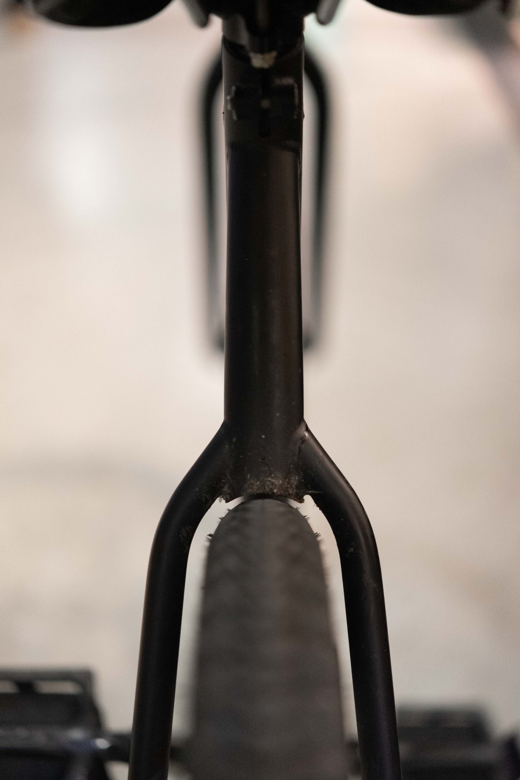 Vue de face d’une fourche noire, avec l’orifice de fixation du frein visible.