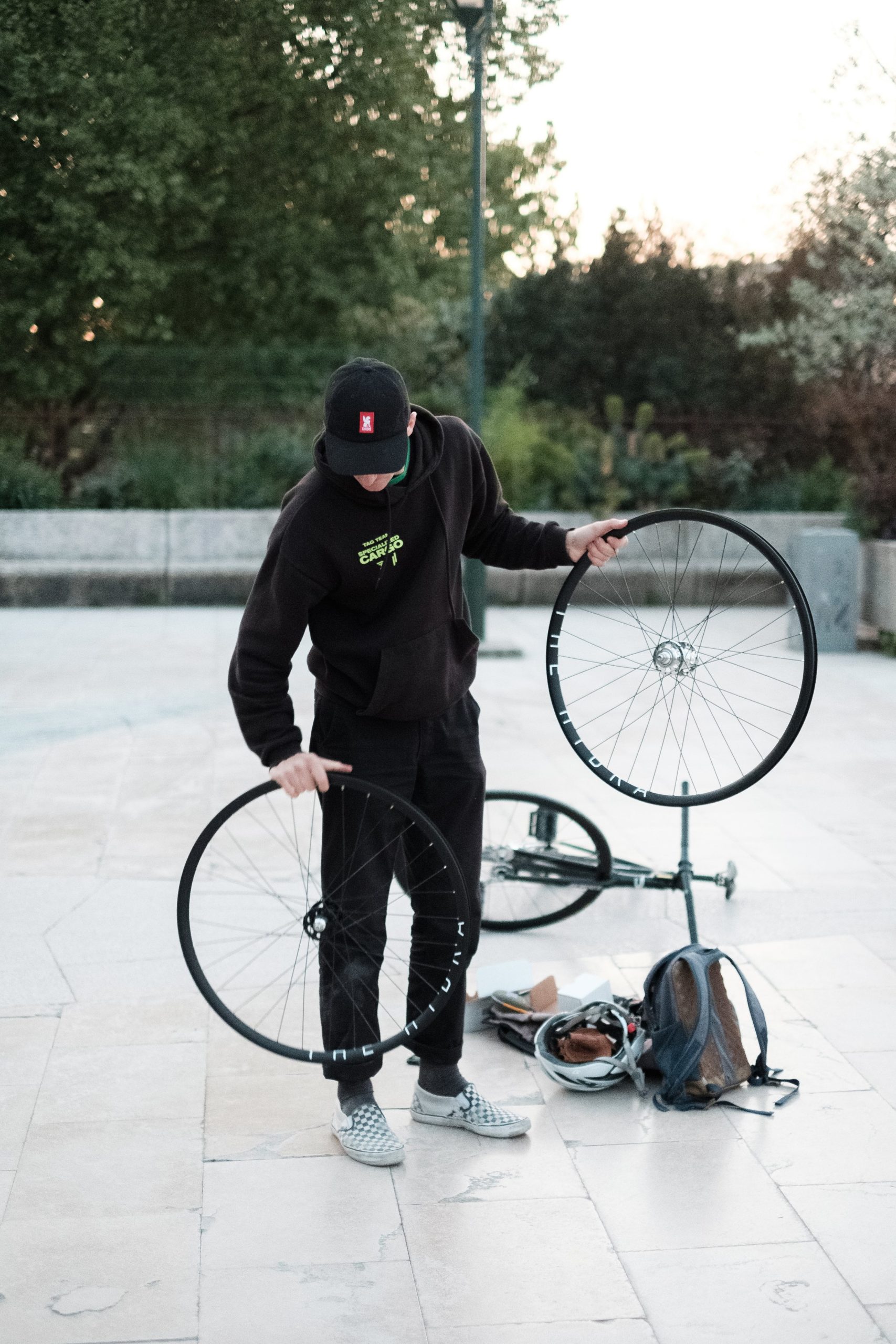 Personne tenant une roue à côté d’un vélo et d’outils au bord de la Seine.