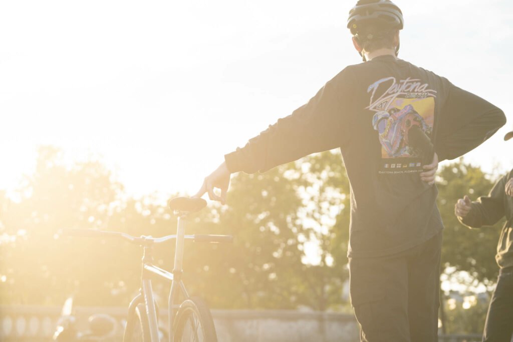 Jackson debout sur son vélo, à contre-jour dans le soleil bas.
