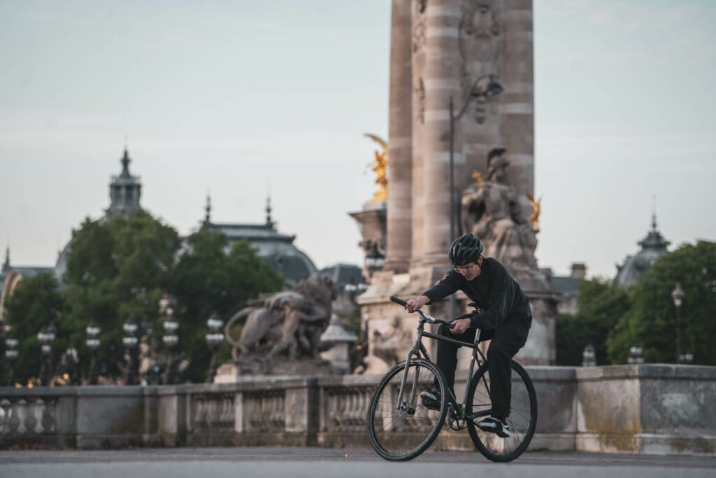 Jackson roule près d’une colonne en pierre sur une esplanade parisienne.