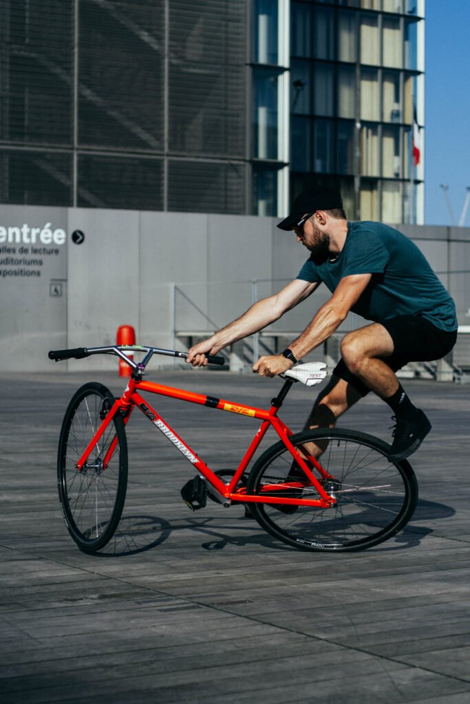Rider penché sur un pignon fixe rouge sur une place pavée.